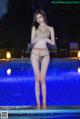 A woman in a bikini standing next to a swimming pool.