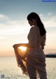 A woman standing in the water at sunset. 