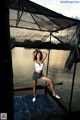 A woman standing on a dock next to a body of water.