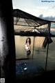 A woman standing on a dock next to a body of water.