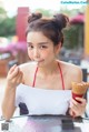 A woman sitting at a table eating an ice cream cone.