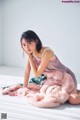 A woman sitting on the floor with a pink blanket.