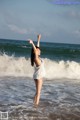 A woman standing in the ocean with her arms outstretched.