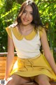 A woman in a yellow dress sitting on a wooden bench.