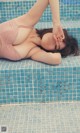 A woman in a pink bathing suit laying on a blue tiled pool.