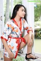 A woman in a floral robe sitting on a window sill.