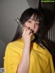 A woman in a yellow shirt drinking from a bottle.