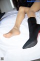 A woman laying on top of a bed wearing black socks and high heels.