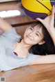 A woman laying on the floor holding a basketball.