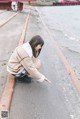 A woman crouching down on the ground pointing at something.