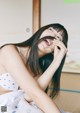 A woman with long black hair sitting on a bed.