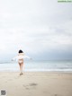 A woman in a white bikini walking on the beach.