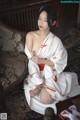 A woman in a white kimono sitting on a chair.