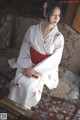 A woman in a white and red kimono sitting on a couch.