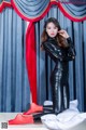 A woman in a black catsuit and red stockings posing for a picture.