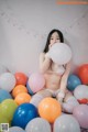 A woman sitting on top of a pile of balloons.