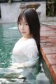 A woman in a white shirt is sitting in a pool.
