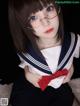 A woman in a sailor outfit with glasses and a red bow tie.