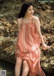 A woman in a red dress sitting on a rock.