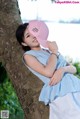 A woman leaning against a tree wearing a pink hat.