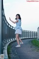 A woman in a blue dress is standing on a bridge.