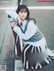 A woman leaning against a pole on the side of the road.