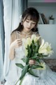 A woman in a white dress holding a bunch of white flowers.