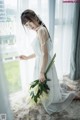 A woman in a white dress holding a bouquet of flowers.