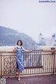 A woman in a blue dress standing on a balcony.